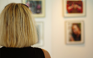 Eine Frau von hinten,die sich Bilder in einem Museum anschaut
