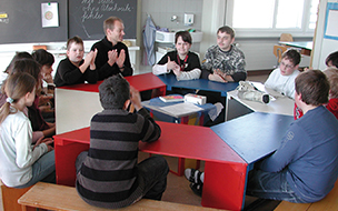 Klasse und Lehrer im Schulzimmer im Kreis sitzend