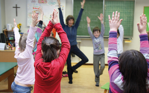 Kinder in einer Schulklasse bei einem Bewegungsspiel.