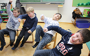 Kinder auf Stühlen sitzend in einer Schulklasse bei einem Beweg