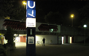 Eingang zu einem U-Bahnhof in der Nacht,ein Mann steht davor.