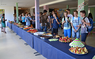 Lange Tischreihe mit verschiedenen Speisen, dahinter stehen Schüler