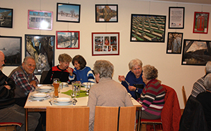 mehrere ältere Personen sitzen essend an einem Tisch