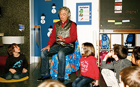 Der Märchenerzähler sitzt auf einem Stuhl,die Kinder hören zu.