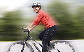 Lächelnde Radfahrerin mit Helm auf ihrem Fahrrad
