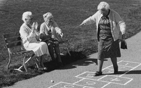 Eine ältere Frau im aufgezeichneten Spielfeld von "Himmel und Hölle"